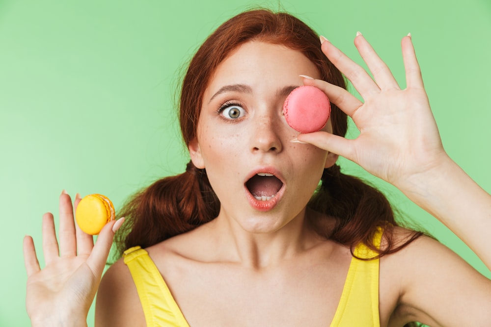 a woman holding two macaroni and cheese balls in front of her face