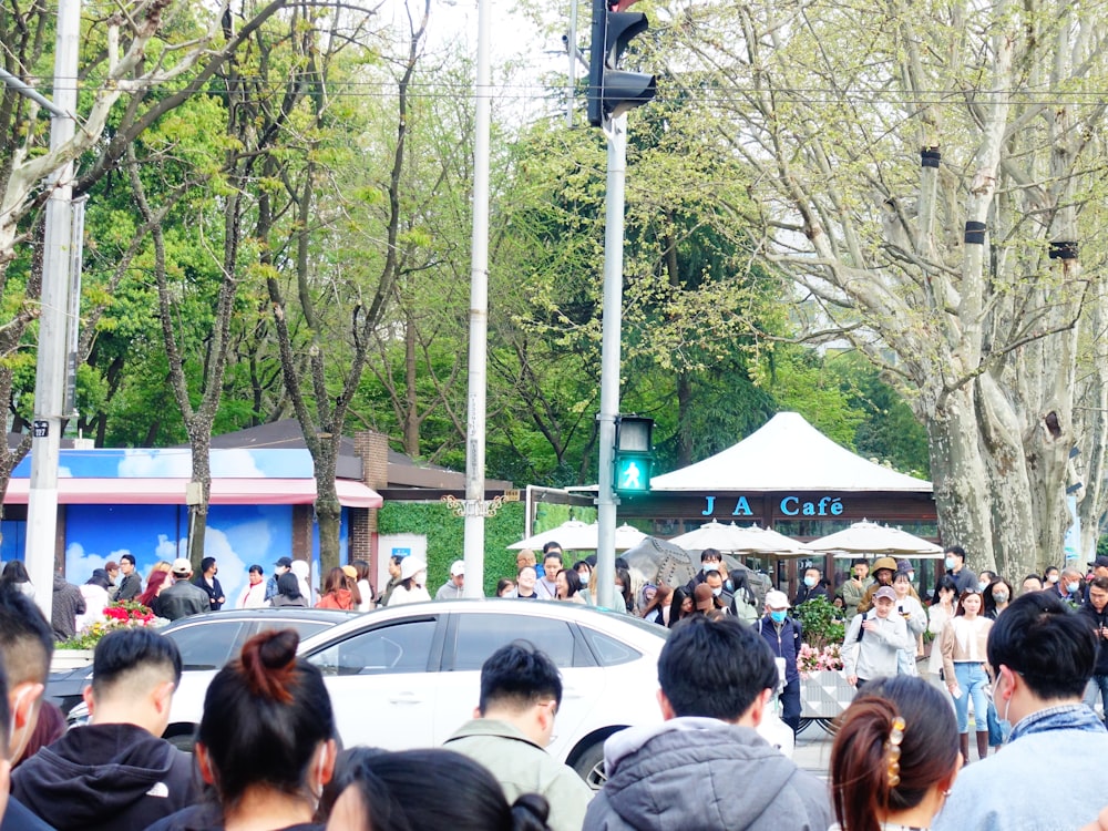 a crowd of people walking down a street next to a traffic light