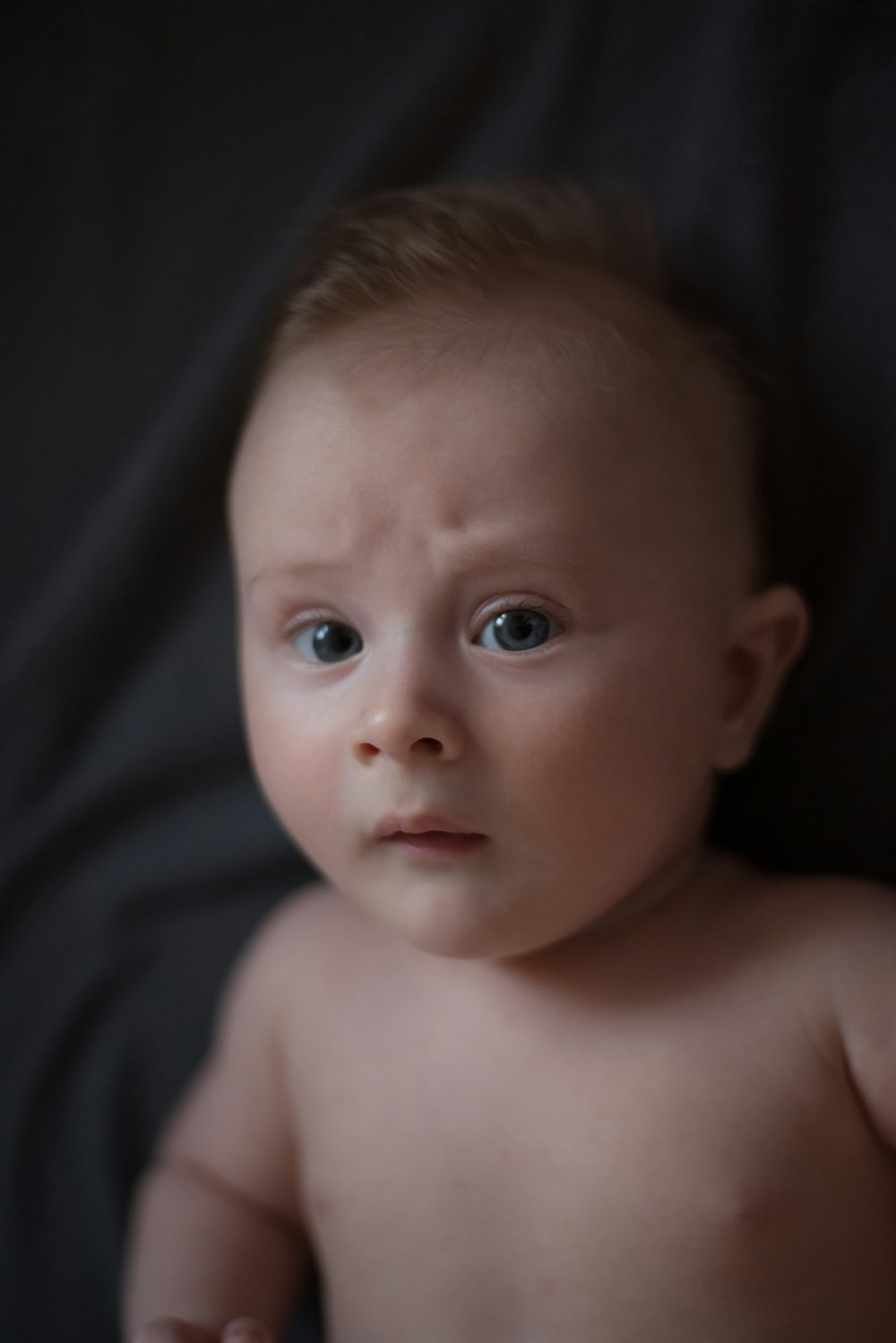 a naked baby with blue eyes looking at the camera