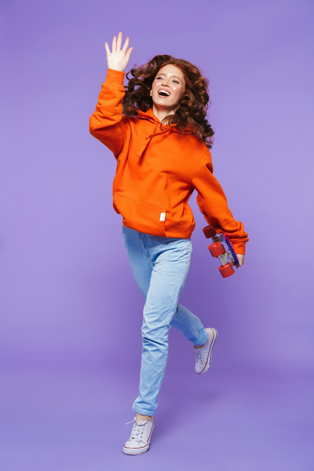 a woman in an orange hoodie jumping in the air