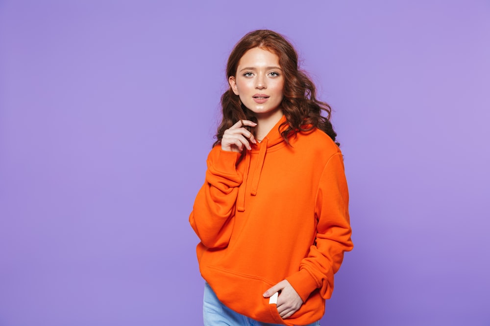 a woman in an orange hoodie posing for a picture