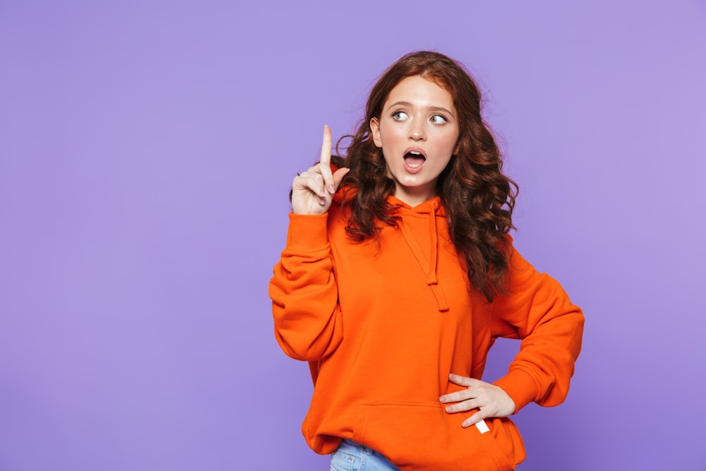 a woman in an orange hoodie making a funny face