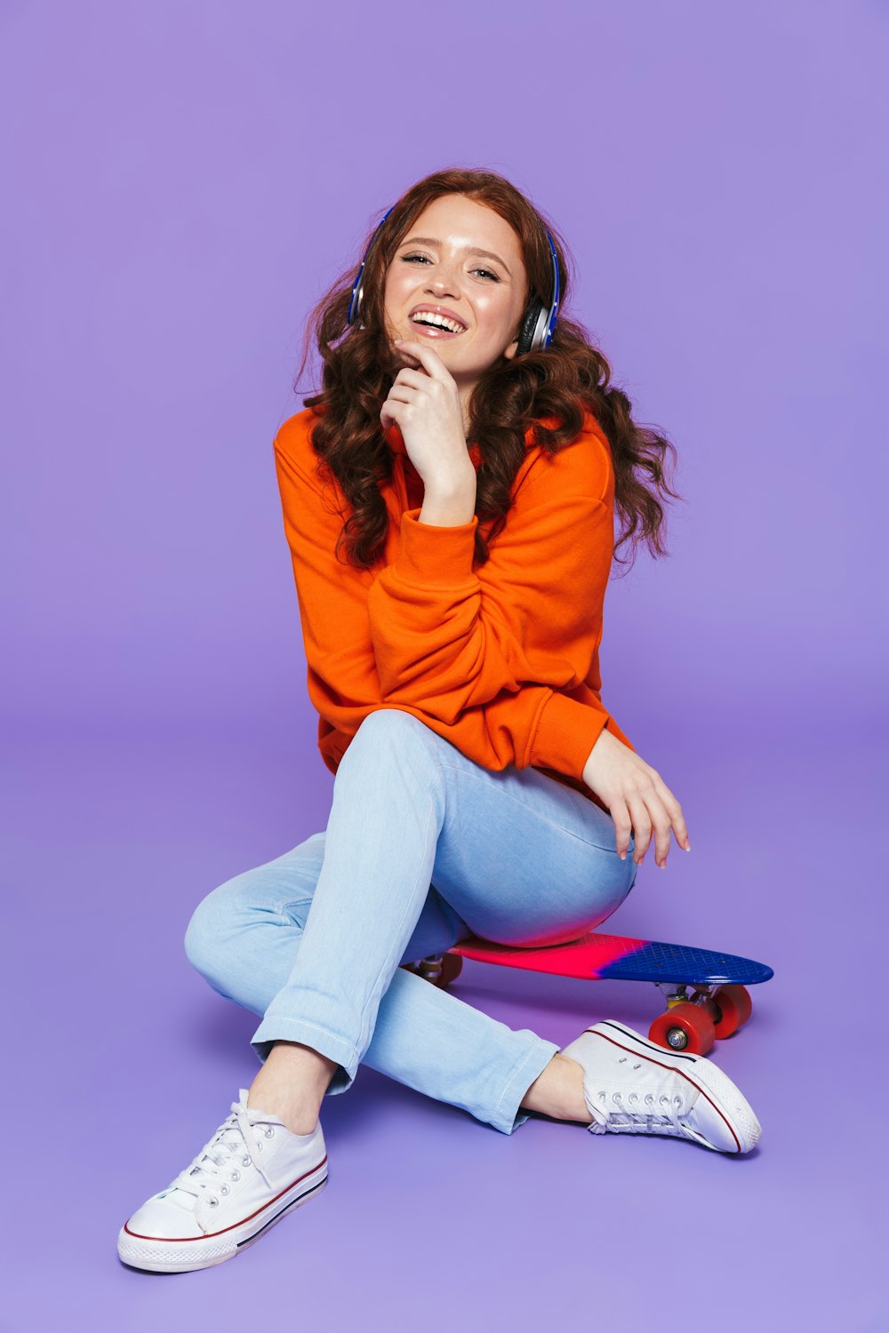 a woman sitting on the ground with a skateboard