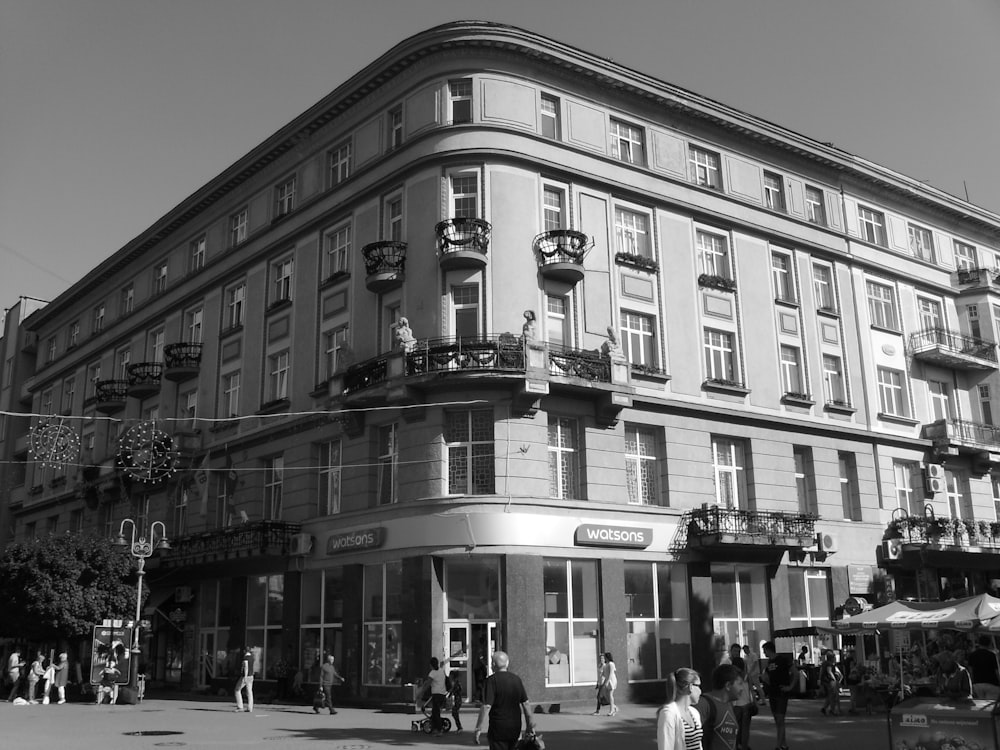 a black and white photo of people walking in front of a building