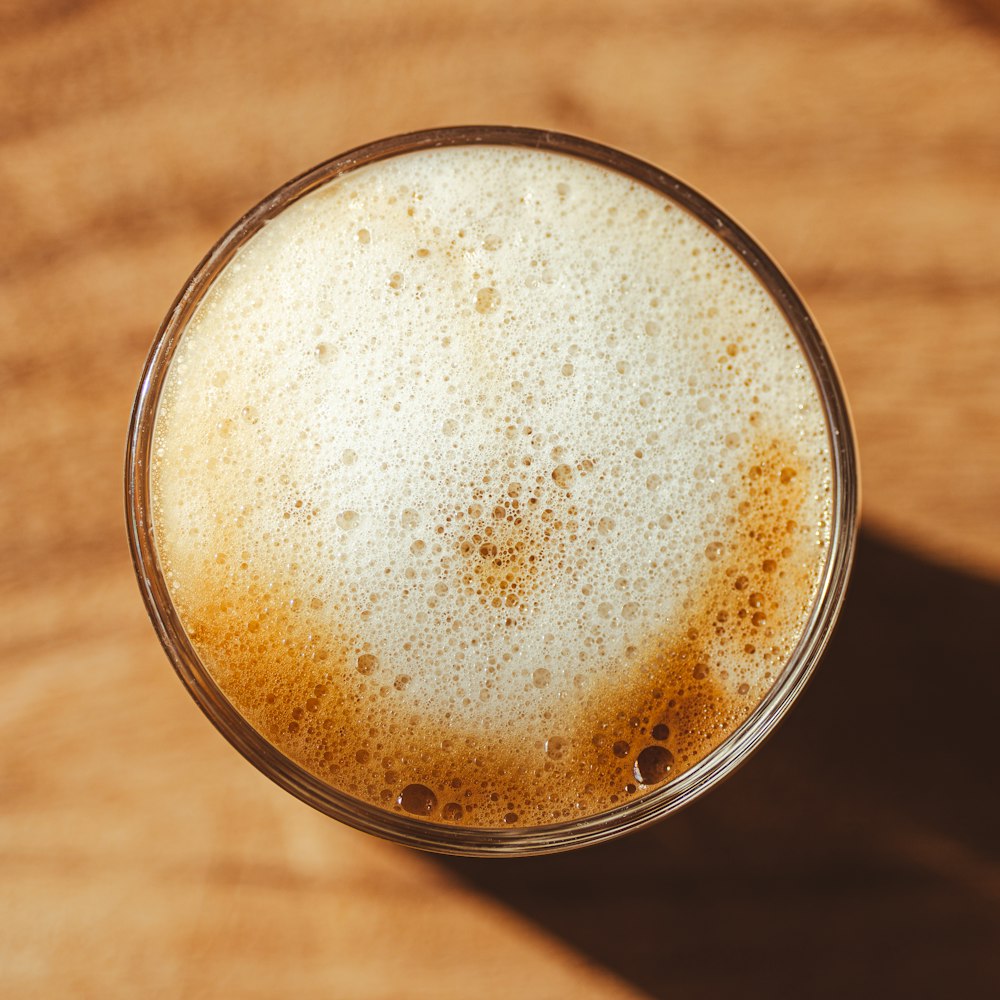 a glass of beer sitting on top of a wooden table