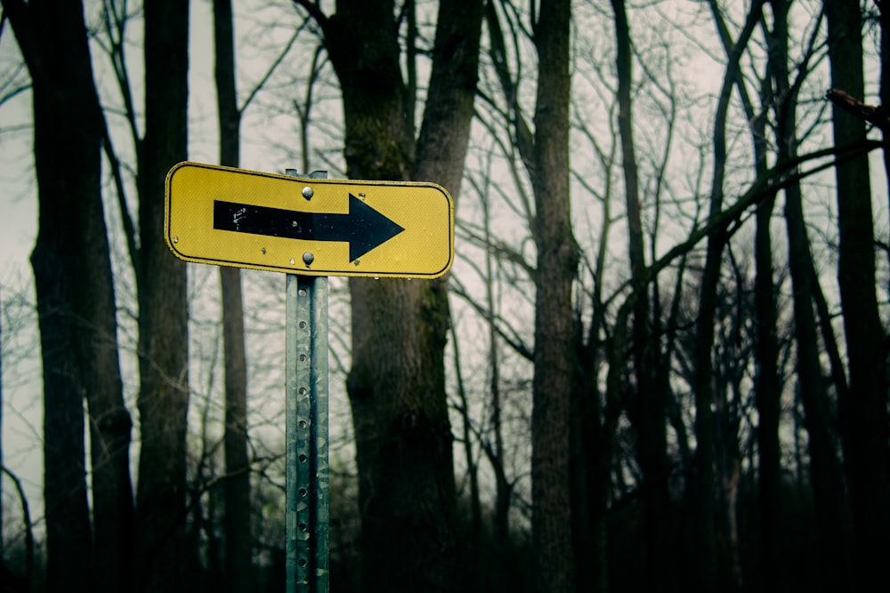 a yellow street sign with an arrow pointing to the right