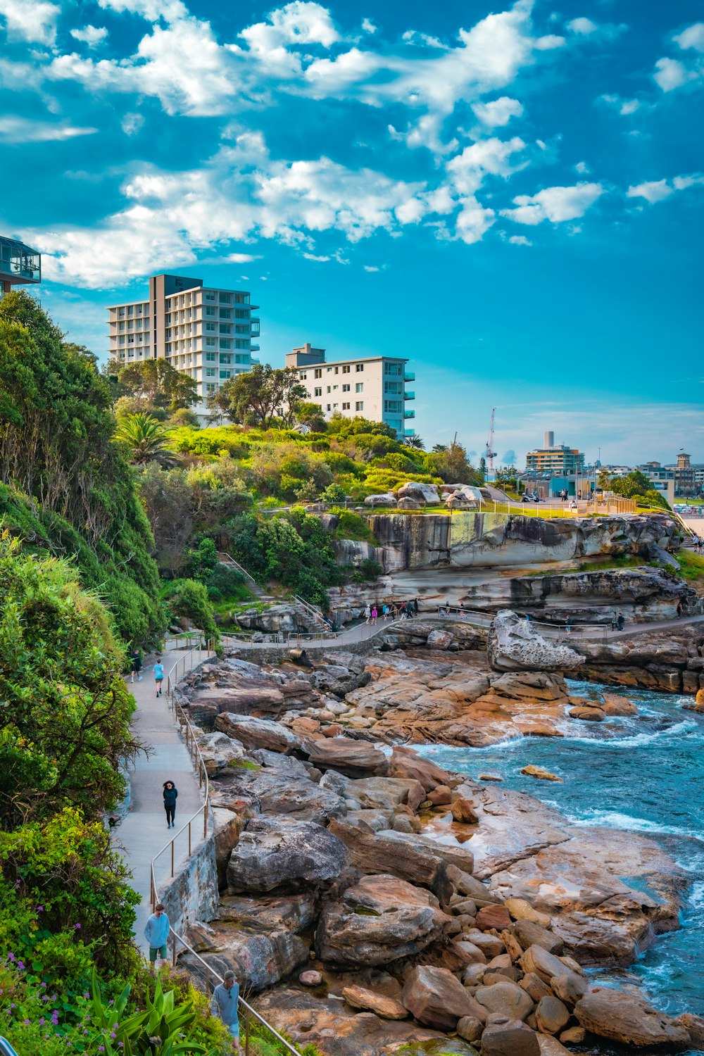 a scenic view of a rocky coastline with people walking on it