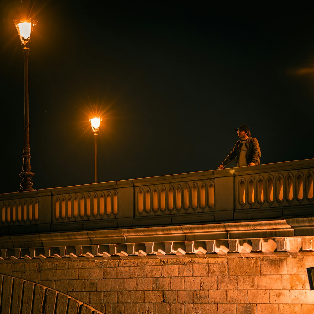 a man sitting on a bridge at night