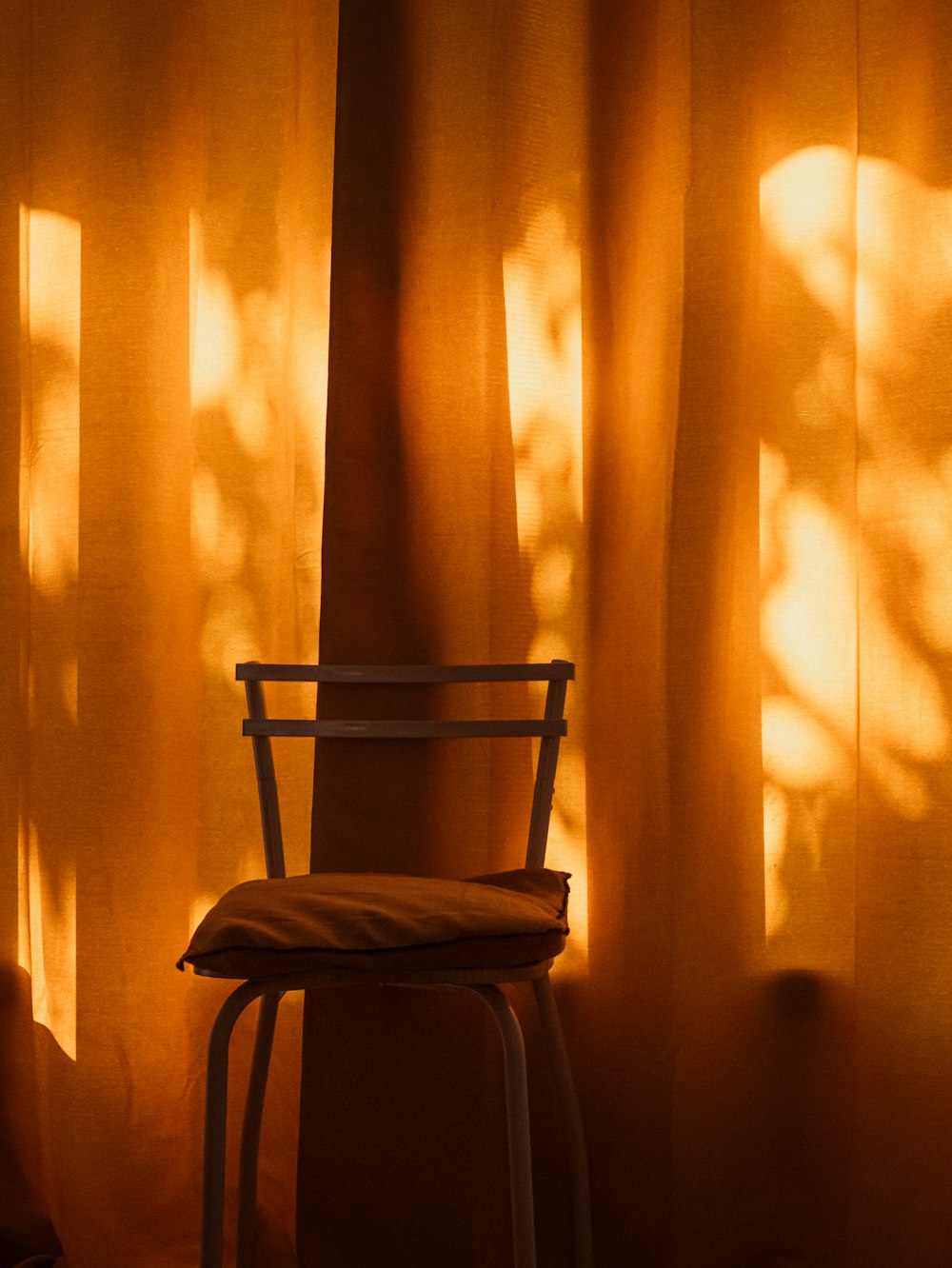 a chair sitting in front of a curtained window