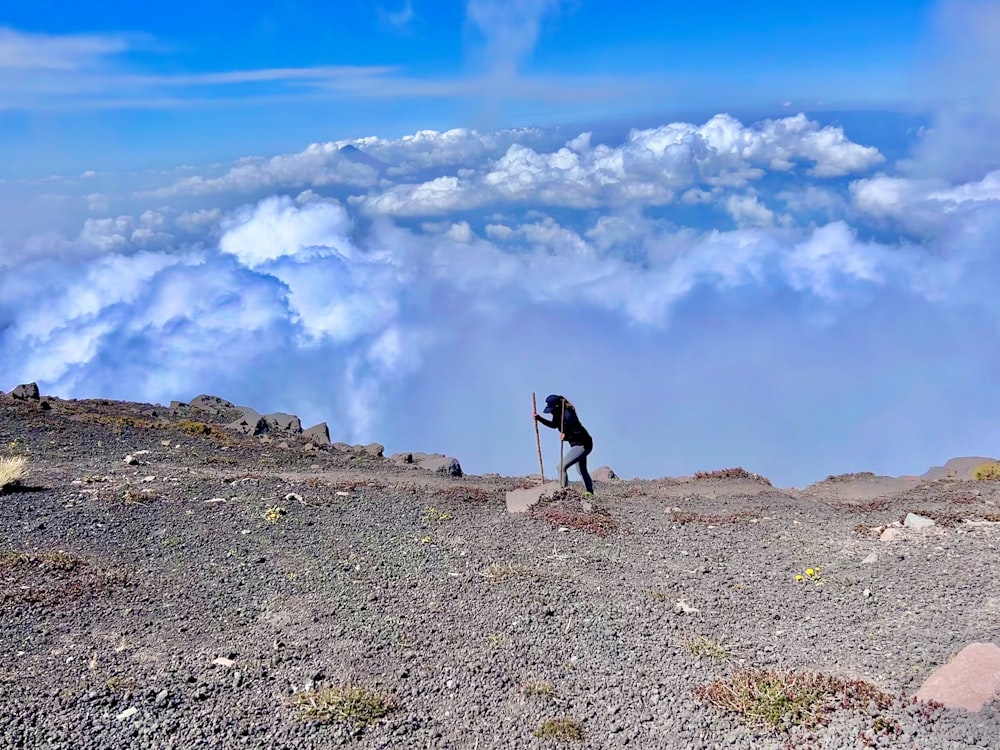 a man standing on top of a mountain holding a stick