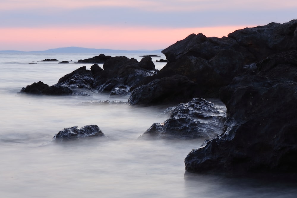 a long exposure of the ocean with rocks in the foreground