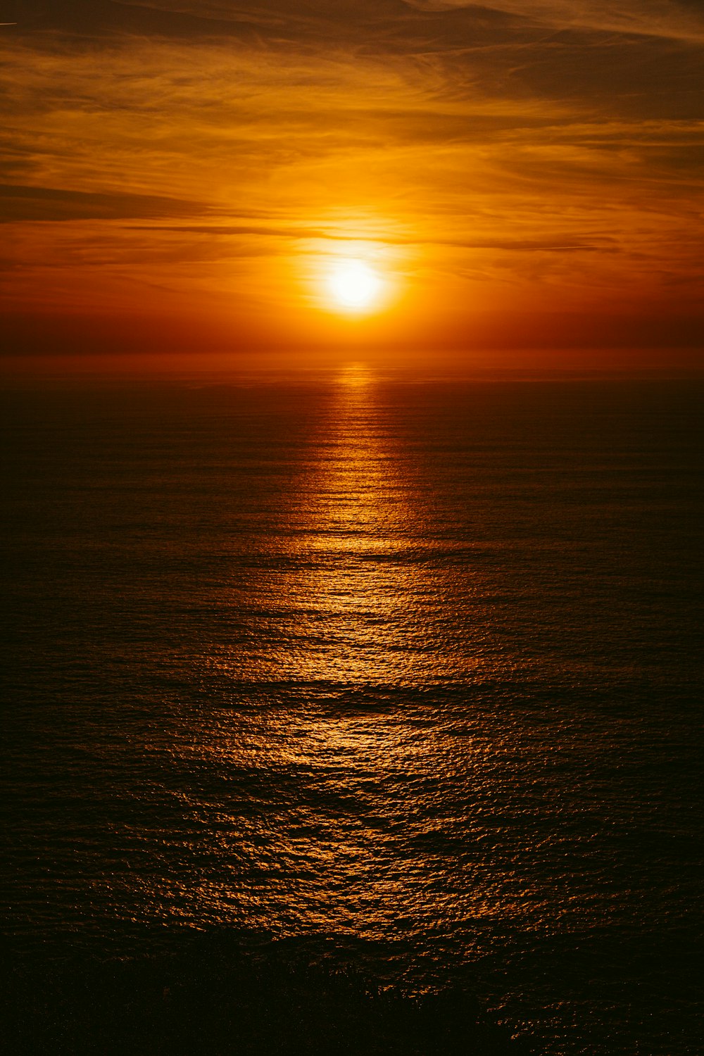 the sun is setting over the ocean on a cloudy day