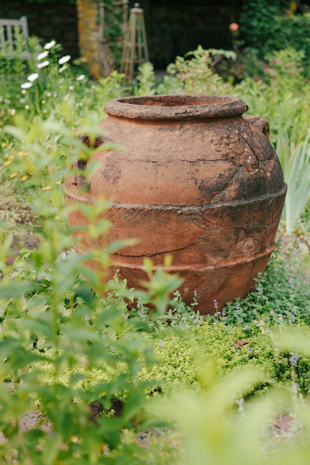 una gran vasija de barro en medio de un jardín