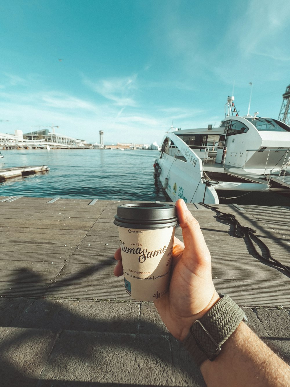 a person holding a cup of coffee on a dock