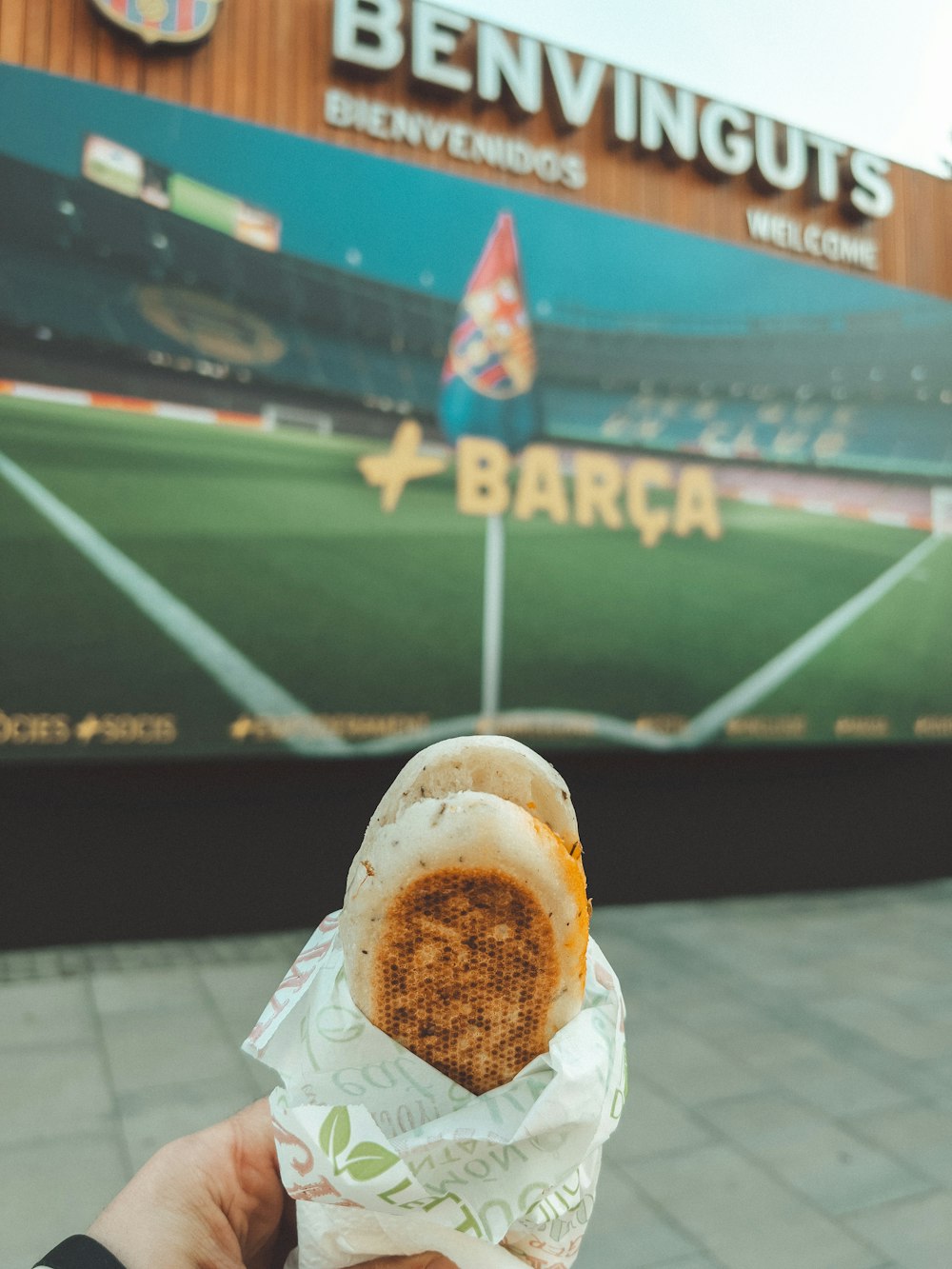 a person holding a sandwich in front of a building