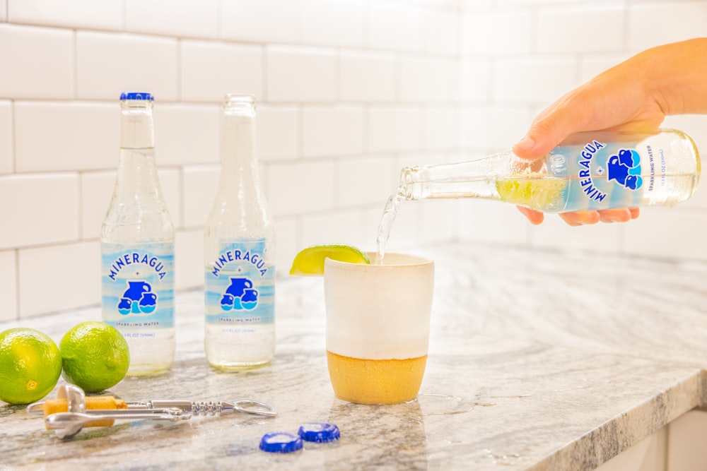 a person pours a drink from a bottle into a glass