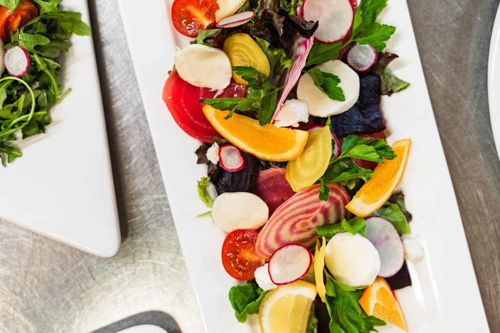 a white plate topped with a salad next to a plate of salad