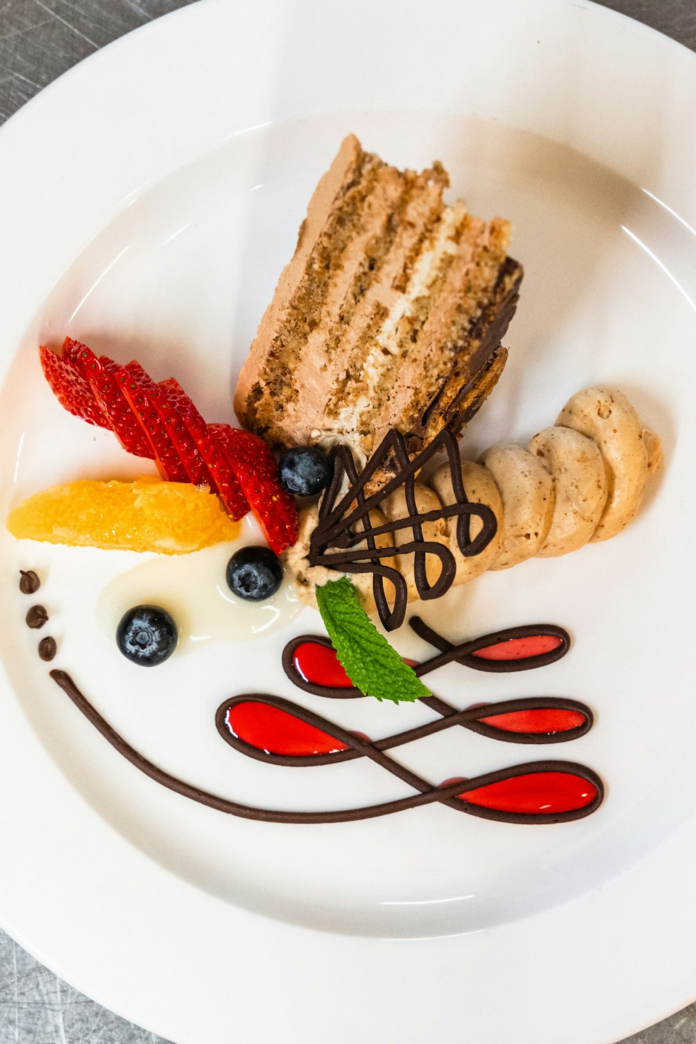 a white plate topped with a piece of cake and fruit