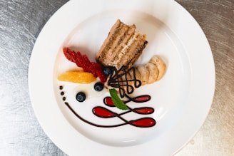 a white plate topped with a piece of cake and fruit