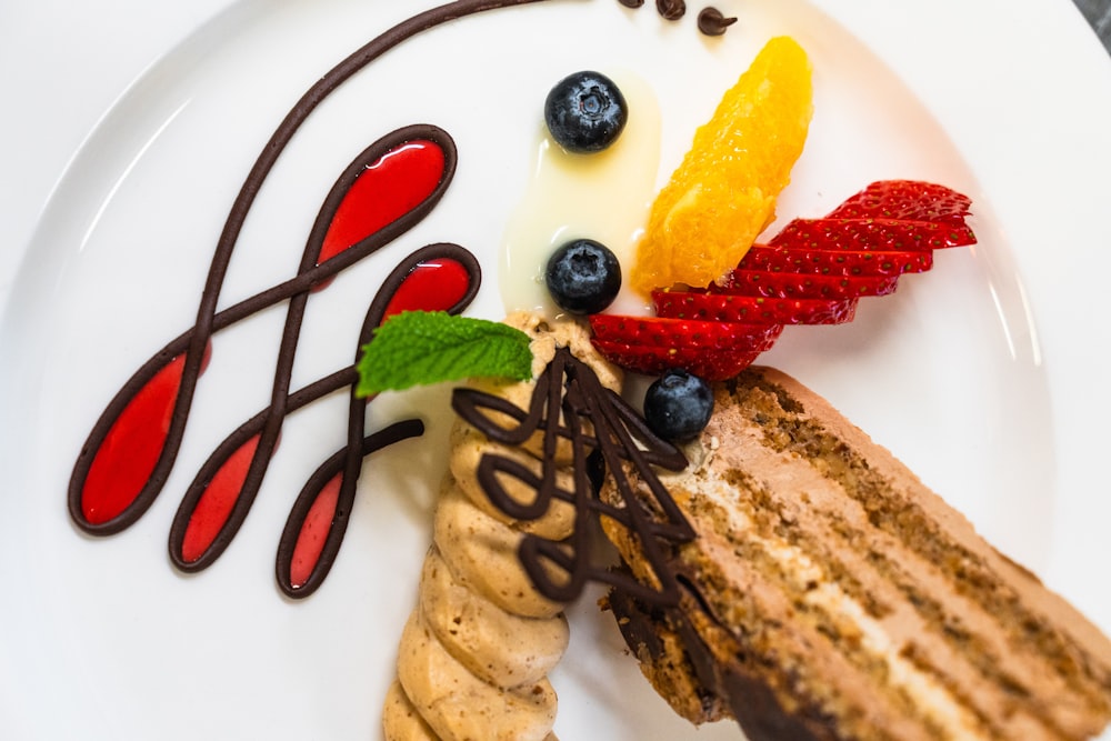 a white plate topped with a piece of cake and fruit