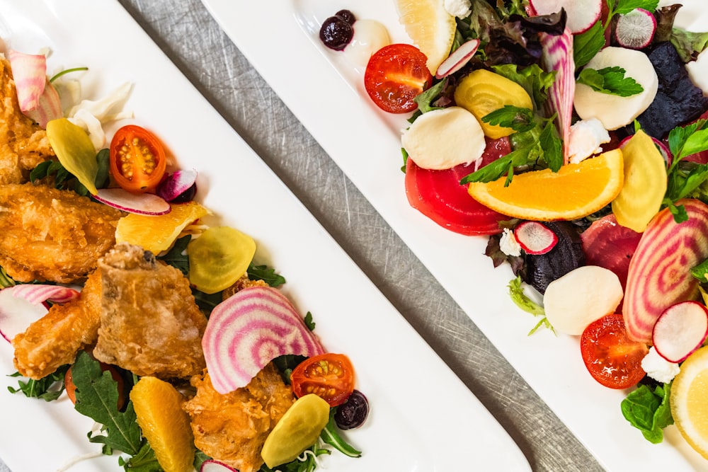 two white plates topped with different types of food