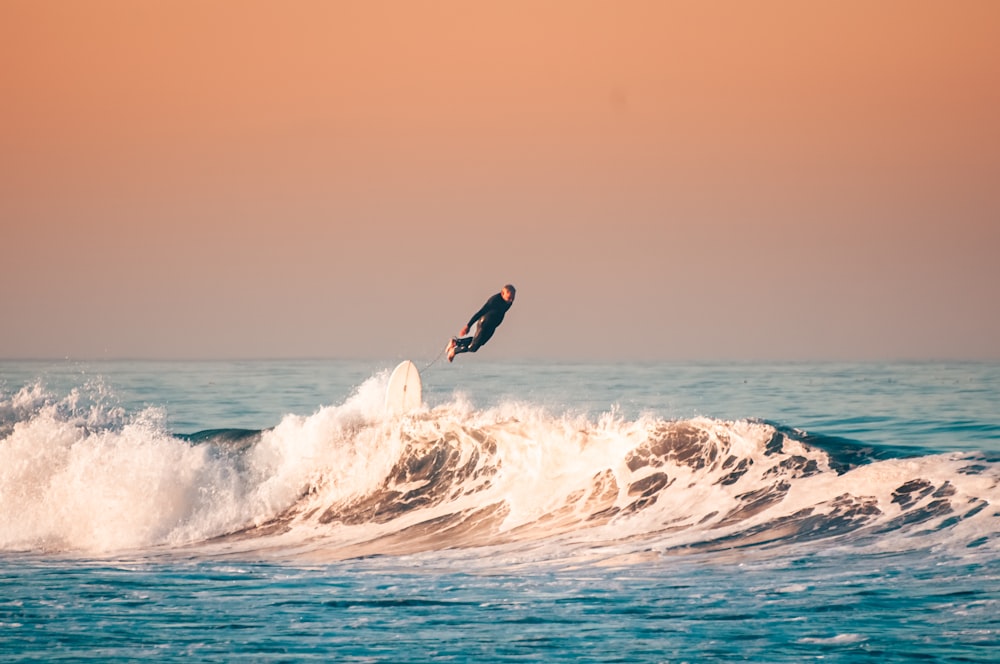 un uomo che cavalca un'onda in cima a una tavola da surf