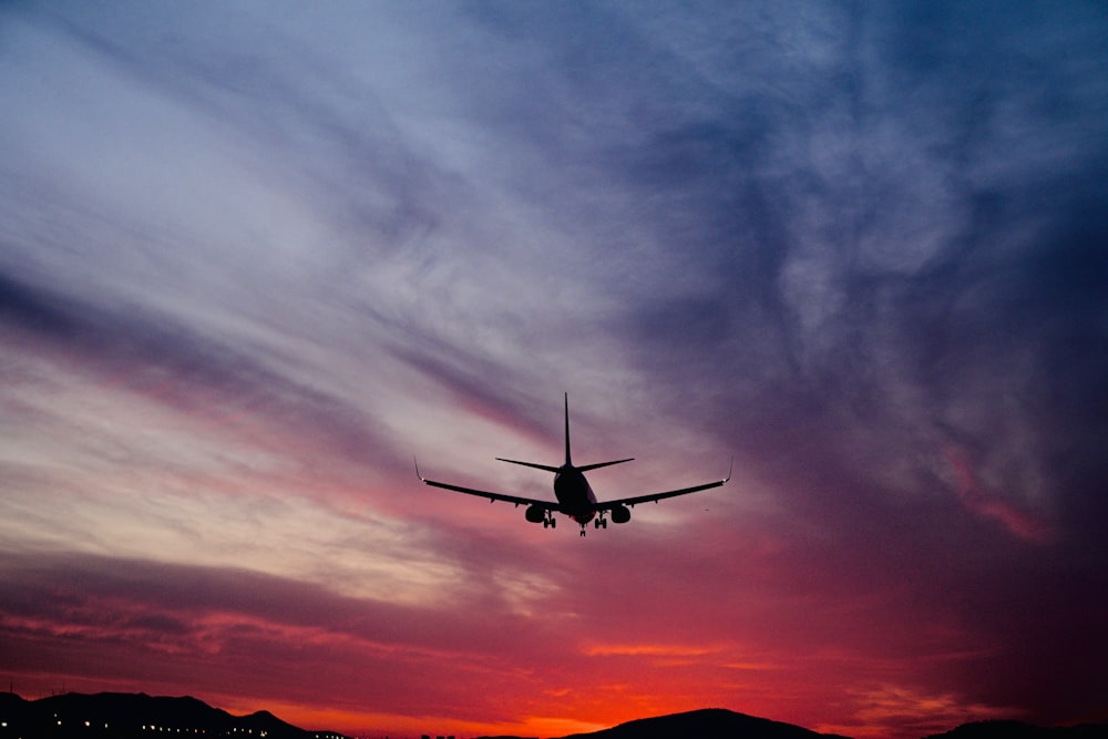 a plane is flying in the sky at sunset