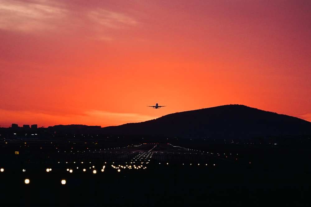 an airplane is flying over a city at sunset