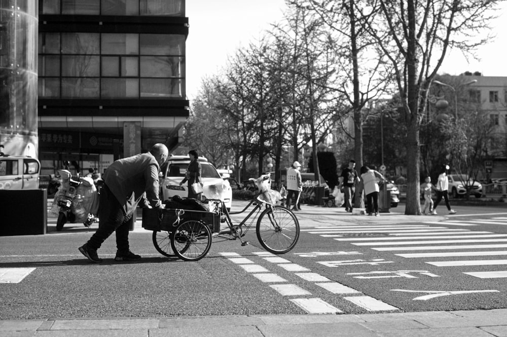 a black and white photo of a man pushing a bike