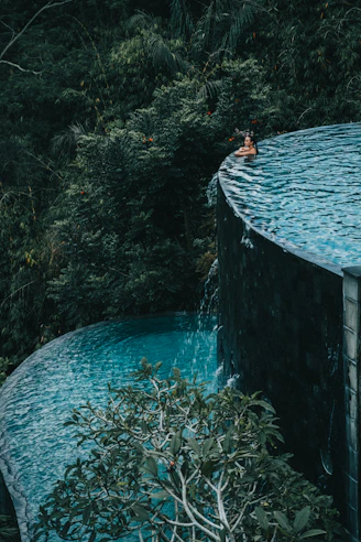 a man swimming in a pool surrounded by greenery