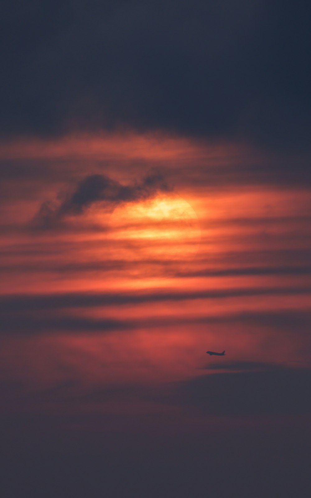 a plane flying in the sky at sunset