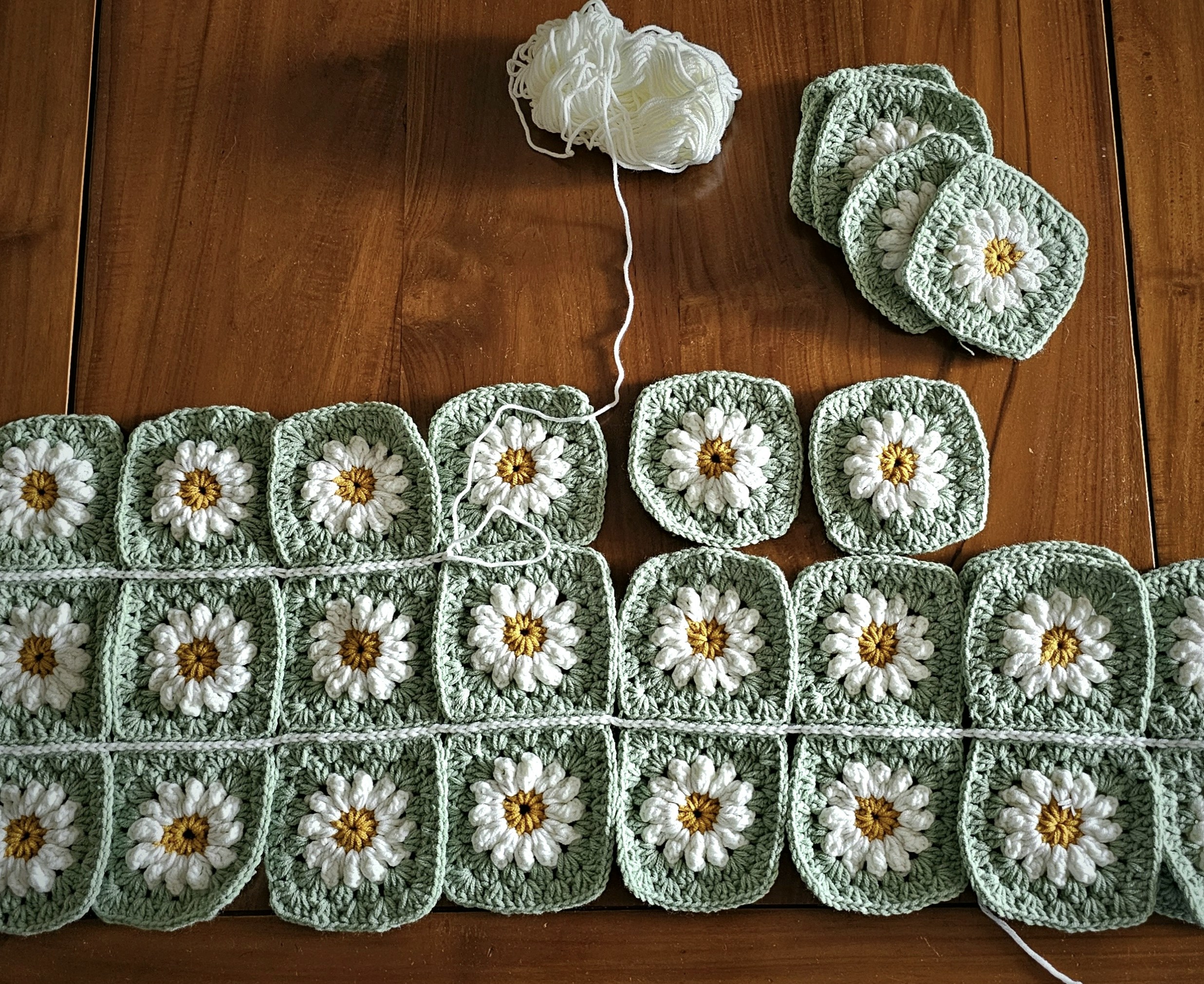 Hand-crocheted daisy flower brooch in cream and yellow thread, pinned to soft fabric