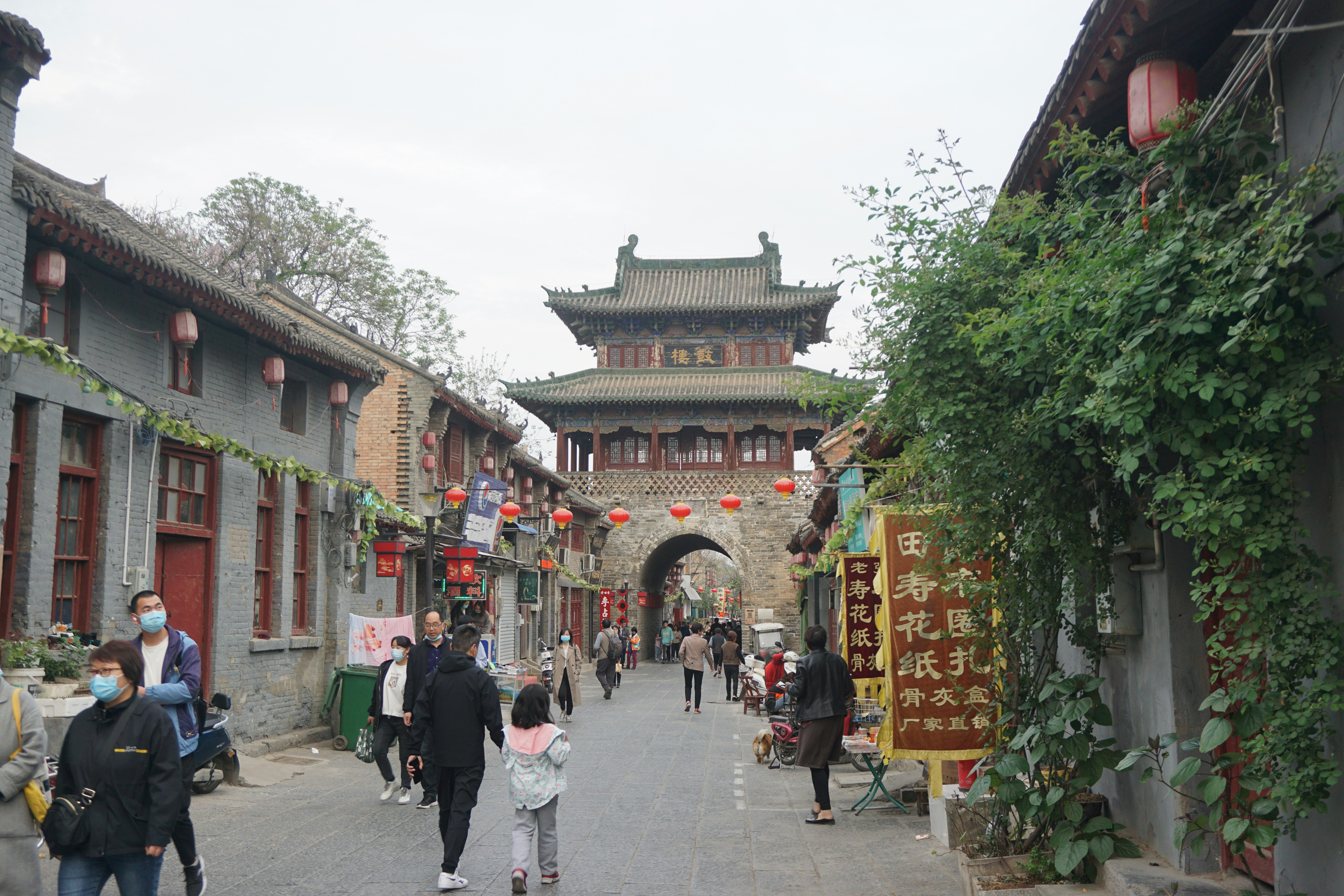 a group of people walking down a street next to tall buildings