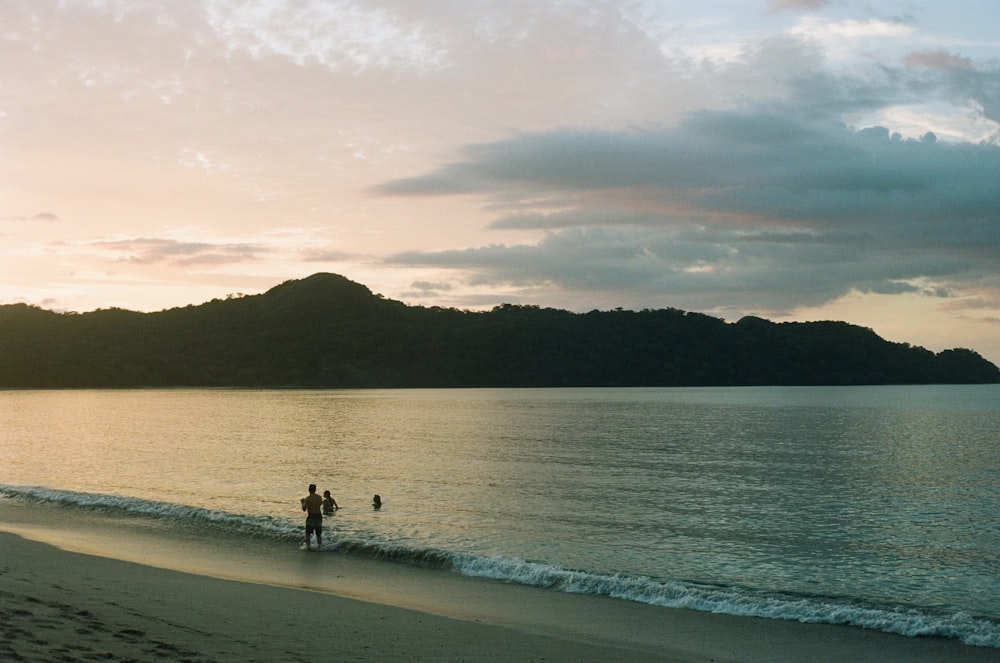 a couple of people standing on top of a sandy beach