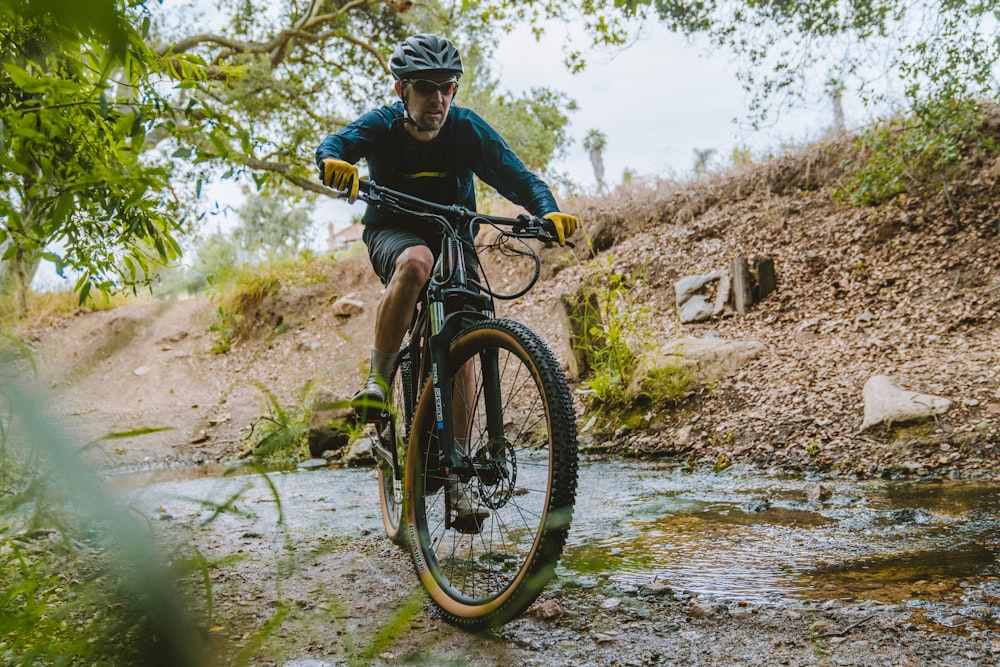 a man riding a mountain bike through a creek