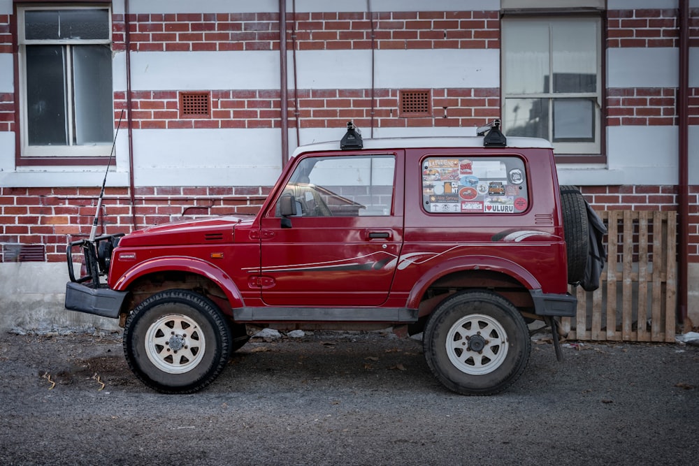 a red jeep parked in front of a brick building
