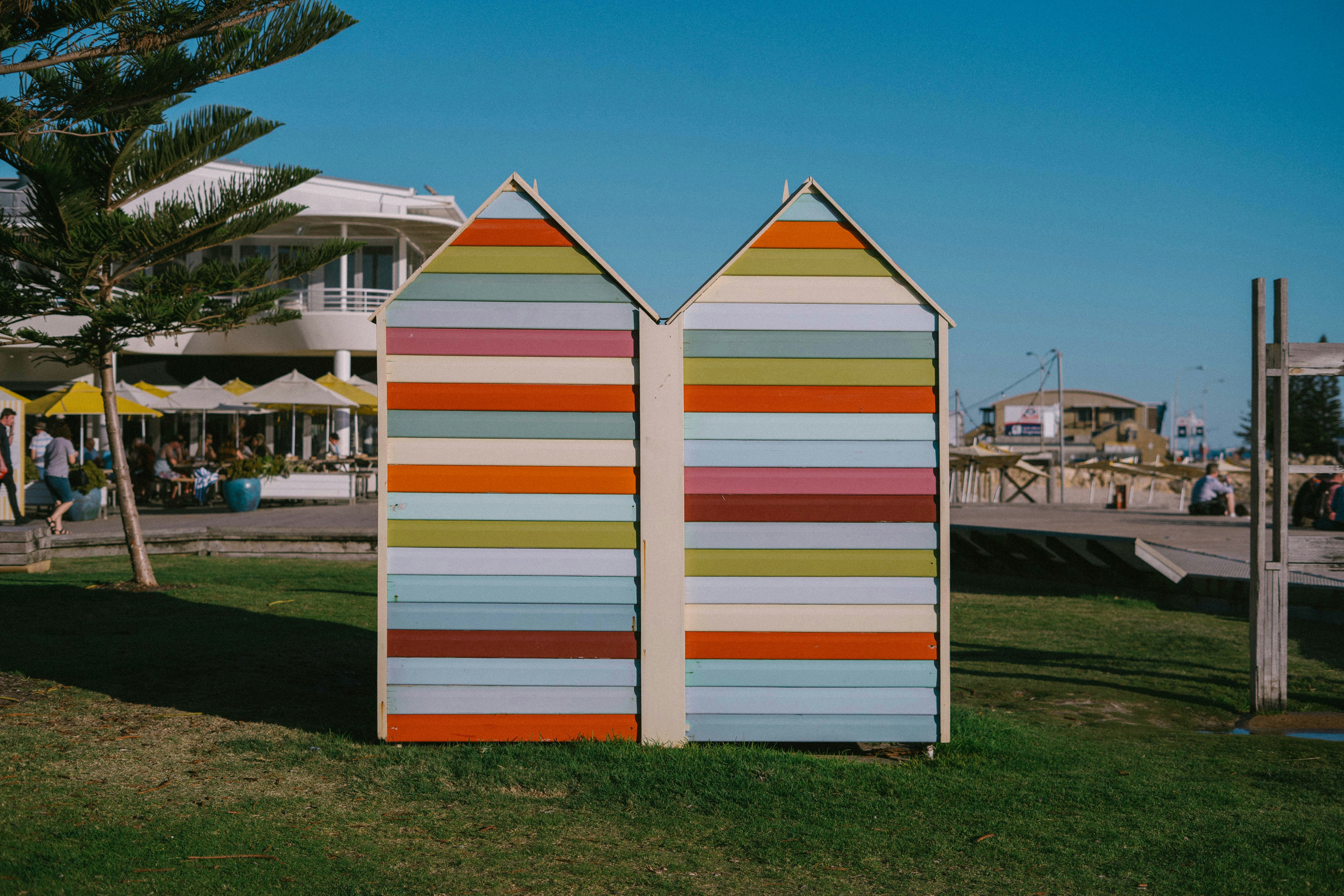 a couple of beach huts sitting on top of a lush green field