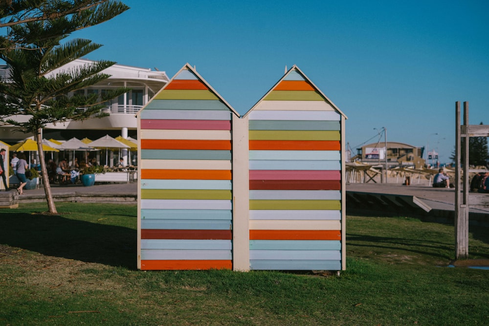 a couple of beach huts sitting on top of a lush green field