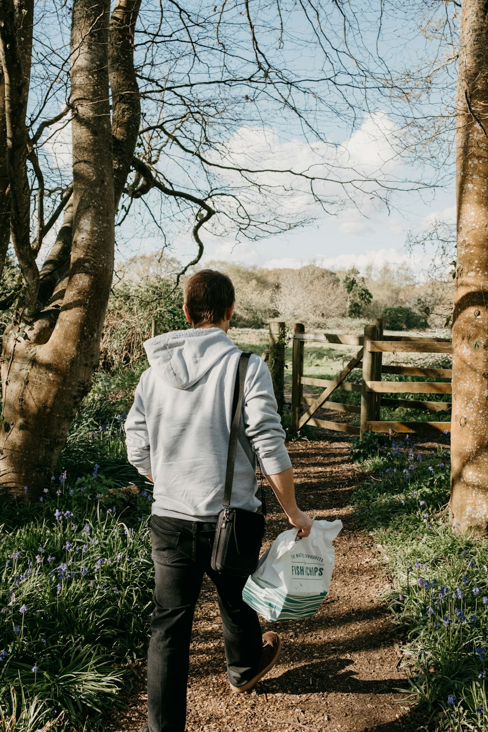 a man walking down a path carrying a bag