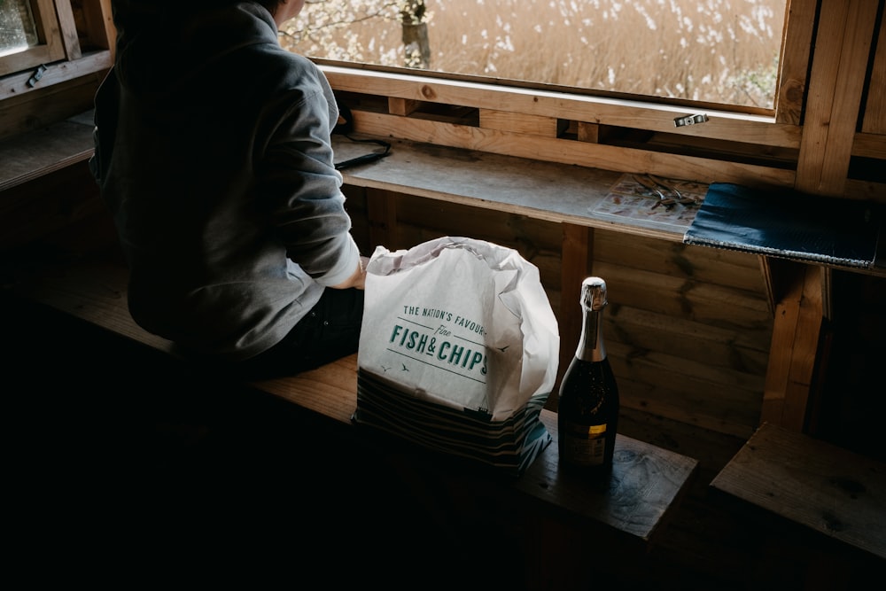 a person sitting at a window sill with a bag