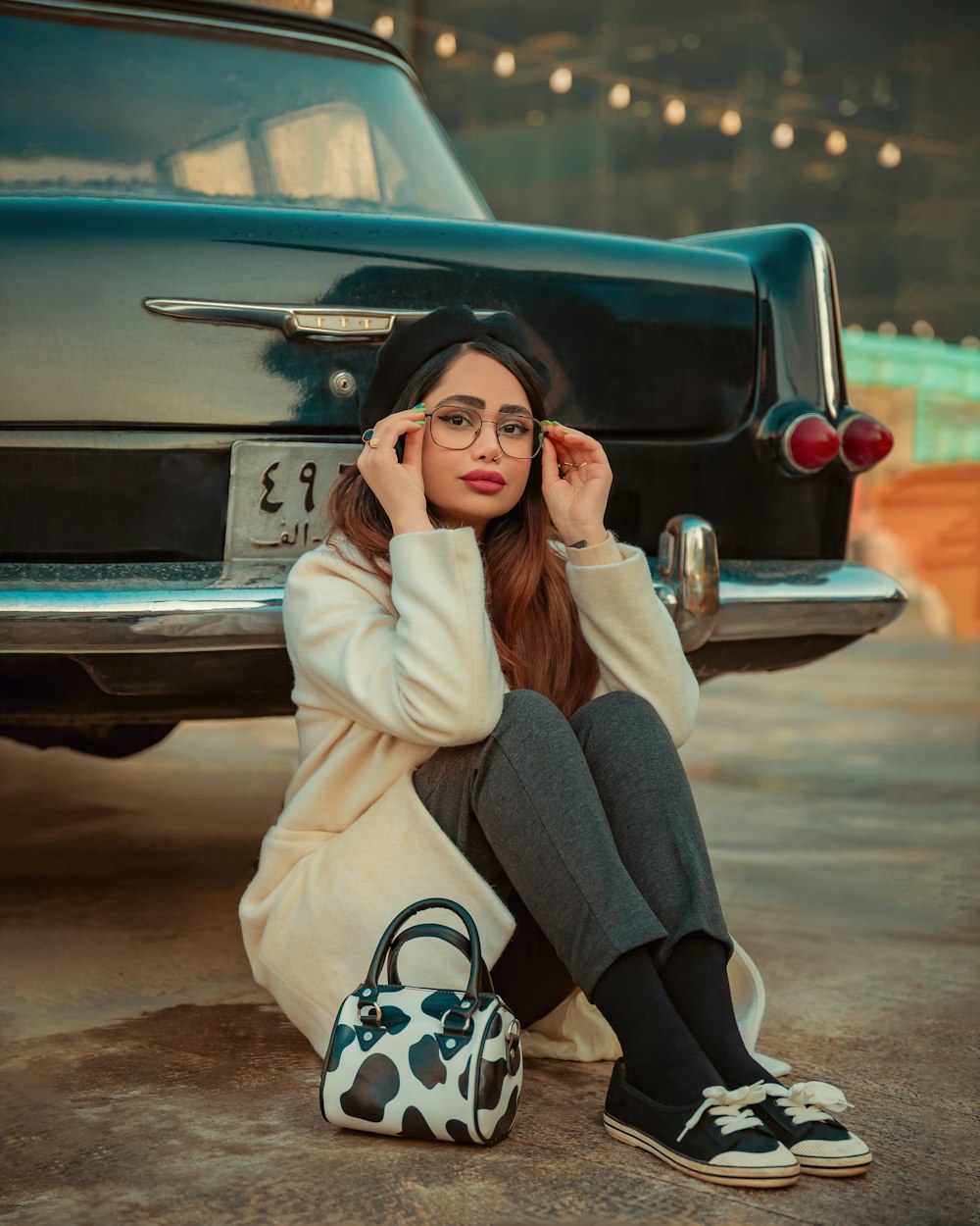 a woman sitting on the ground next to a car