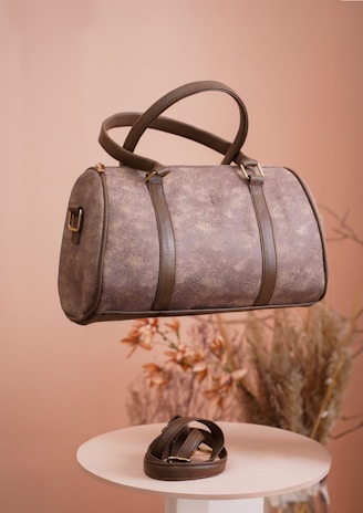 a brown leather bag hanging from a hook on a table