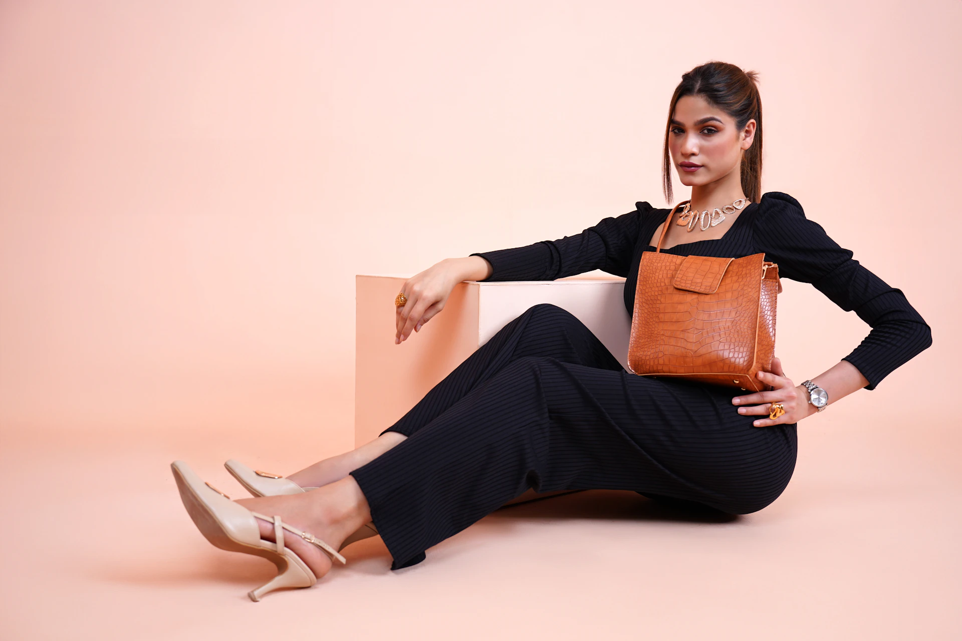 a woman sitting on the floor with a brown purse