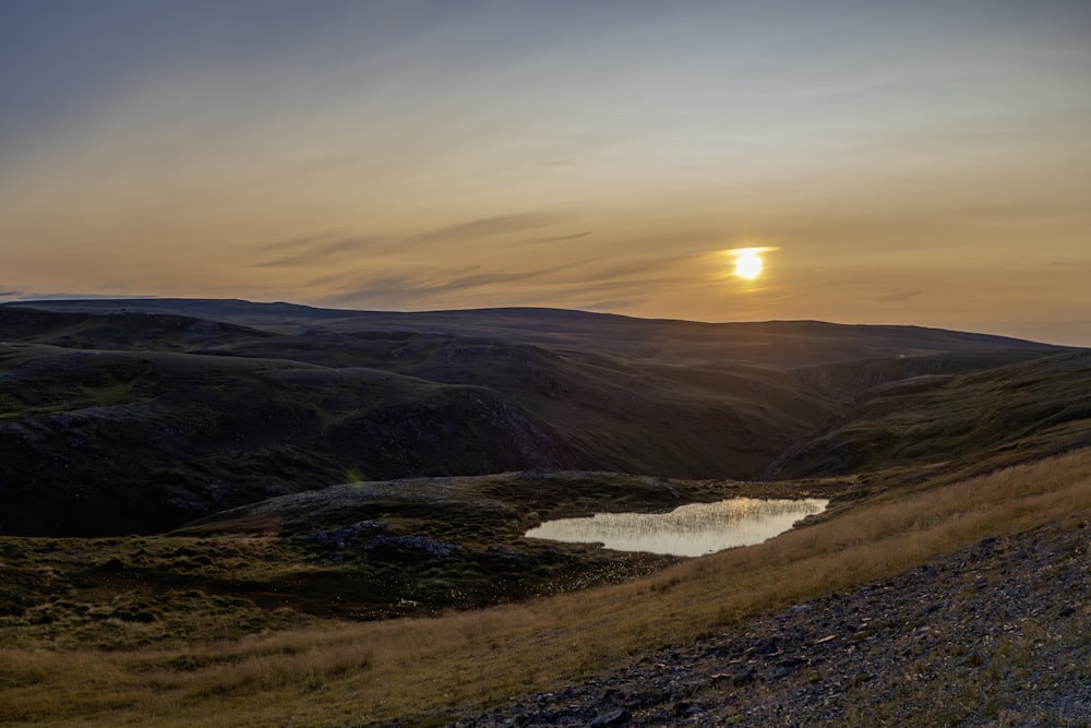 the sun is setting over a small lake in the mountains