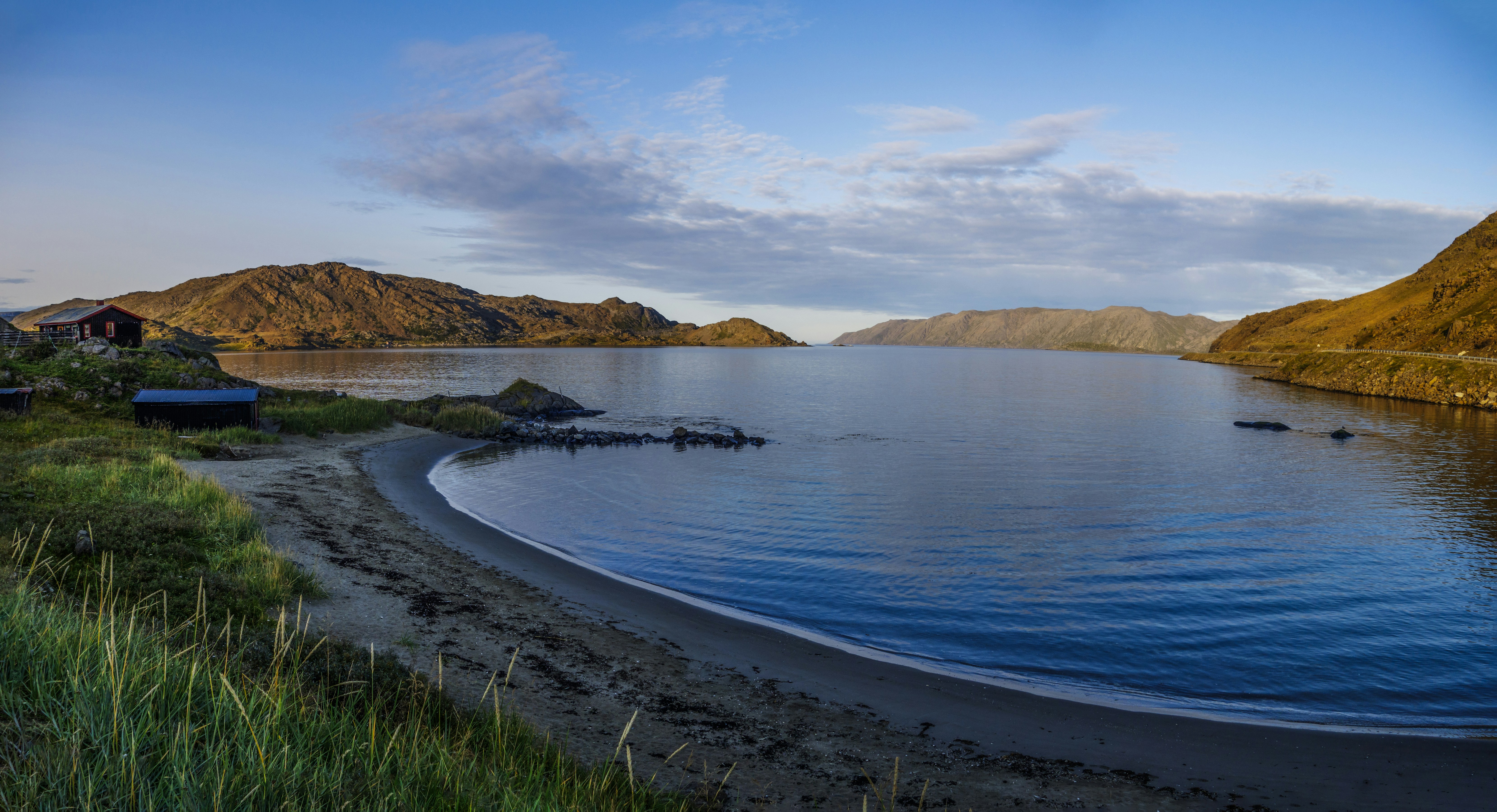 a body of water surrounded by mountains and grass
