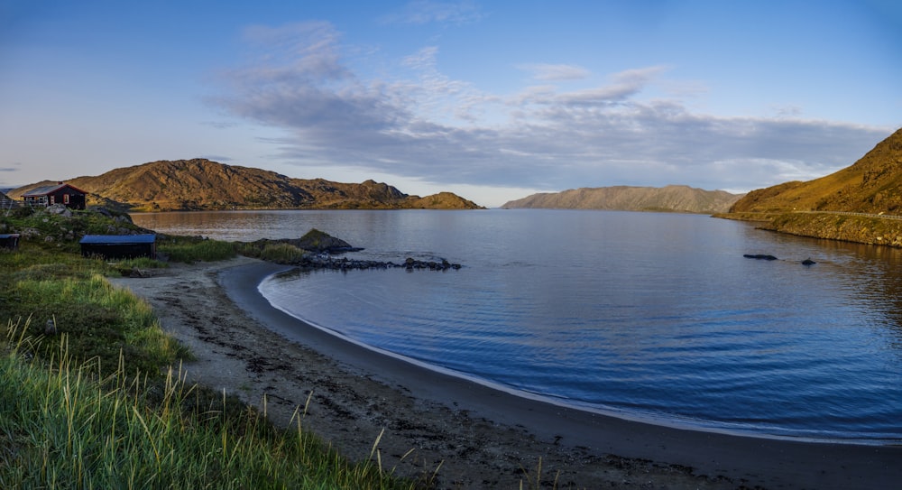 a body of water surrounded by mountains and grass