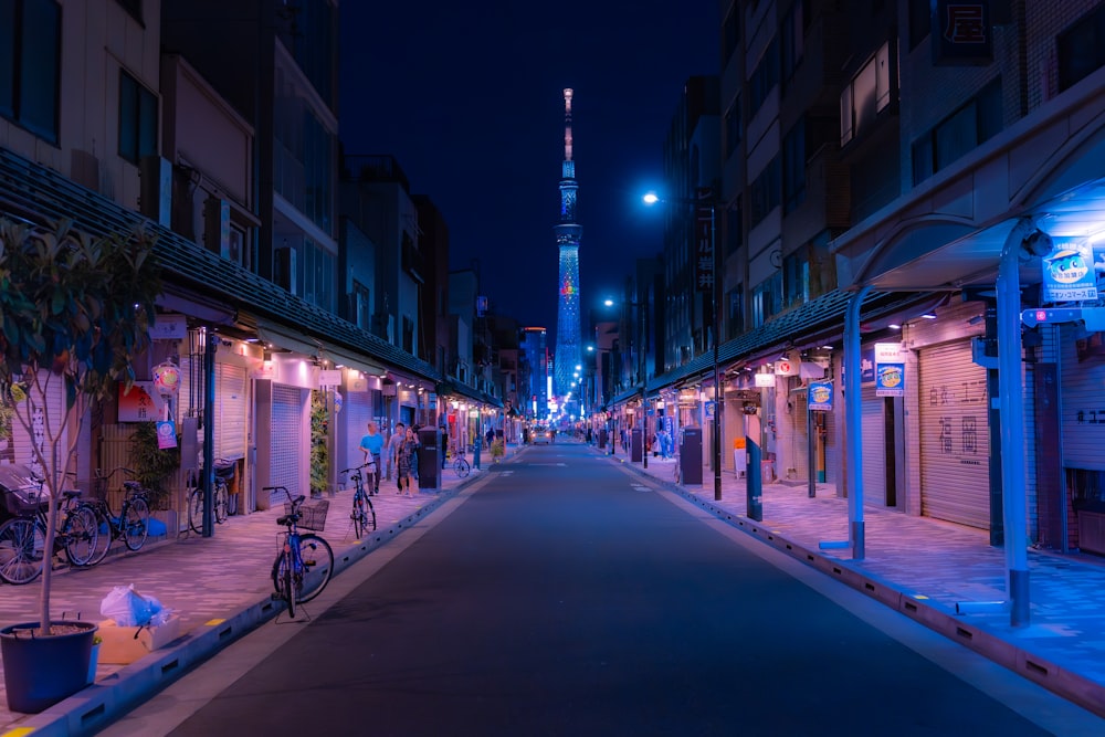 a city street at night with a tall tower in the background