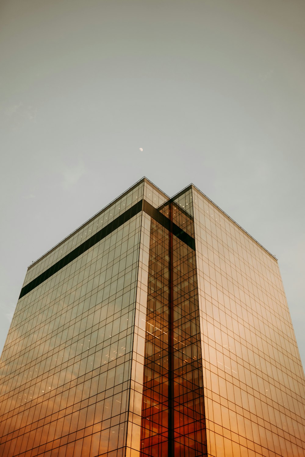 a tall glass building with a sky in the background