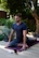 a man sitting on a yoga mat in the middle of a garden