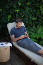 a man sitting in a chair using a cell phone